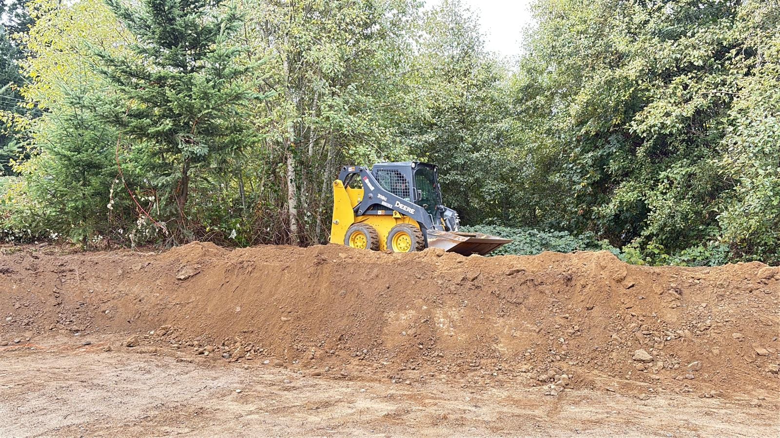 Mini excavator grading, levelling and clearing a site